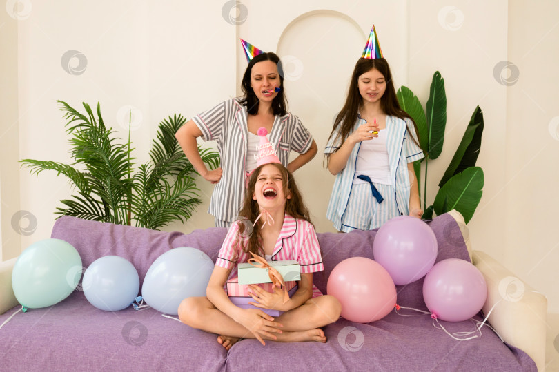 Скачать Смеющаяся семья с праздничными аксессуарами празднует день рождения дома. фотосток Ozero