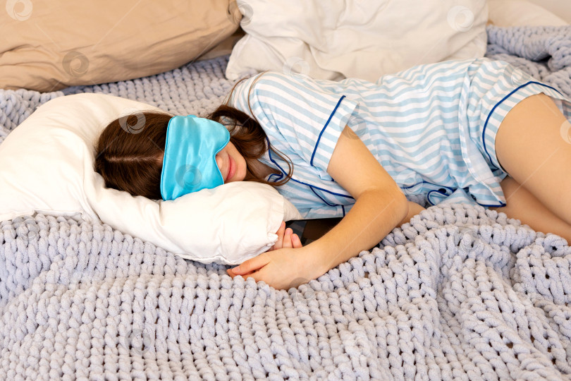 Скачать Девочка-подросток спит в маске для сна в уютной кроватке. фотосток Ozero