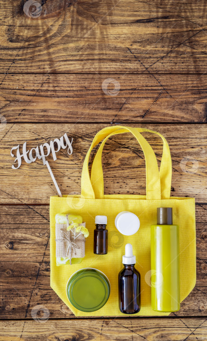 Скачать Желтая хлопчатобумажная сумка со спа-косметикой на деревянном фоне фотосток Ozero