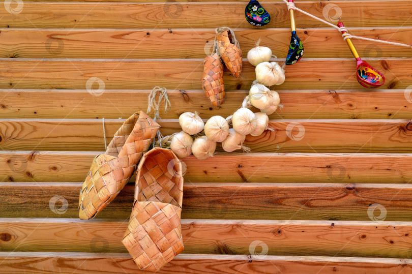 Скачать Русские традиционные старинные лапти с пучком чеснока и веревкой с загнутыми деревянными ложками. Композиция в русском славянском стиле. фотосток Ozero