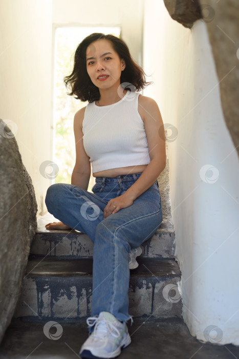 Скачать Молодая вьетнамка сидит на ступеньках фотосток Ozero
