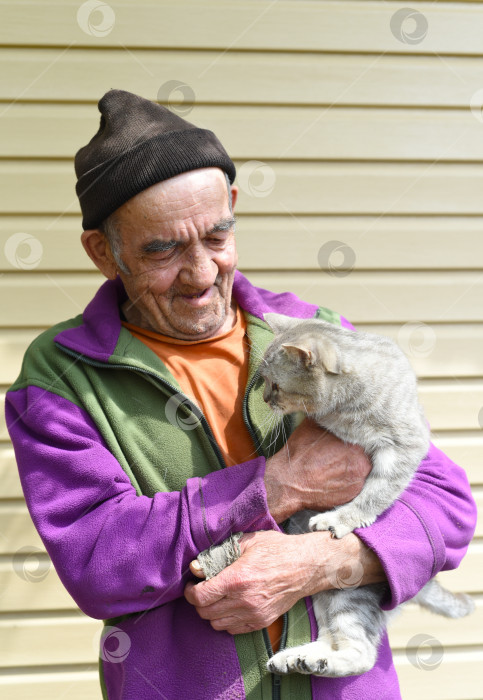 Скачать Старый русский мужчина держит на руках кошку и смеется фотосток Ozero