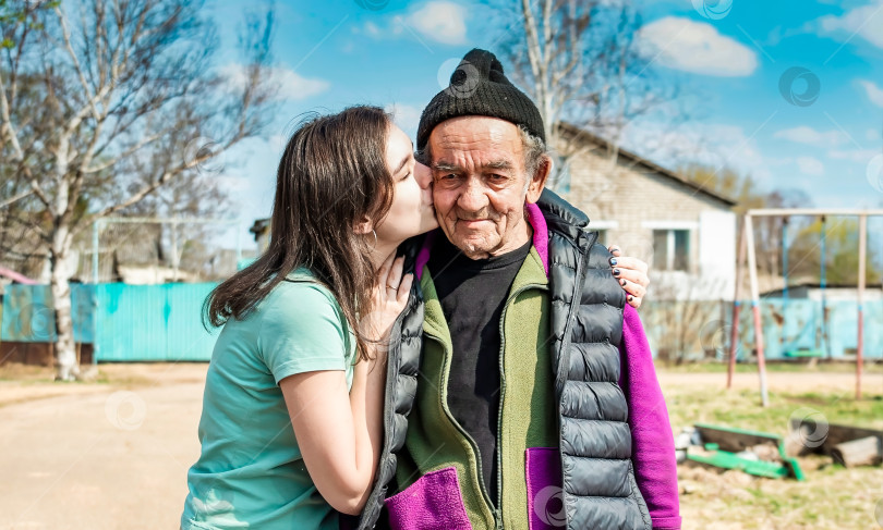 Скачать Портрет внучки, целующей в щеку своего 75-летнего дедушку в русской деревне фотосток Ozero