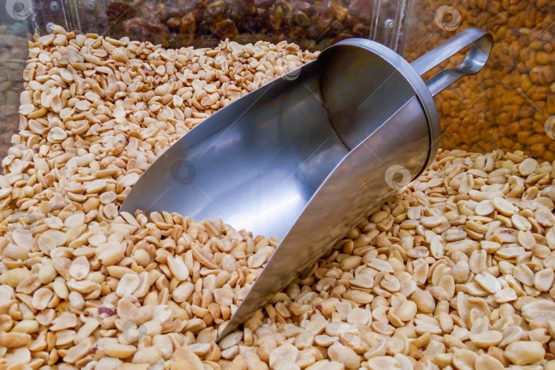 Скачать Горка обжаренного очищенного арахиса с металлической ложечкой на прилавке в супермаркете фотосток Ozero