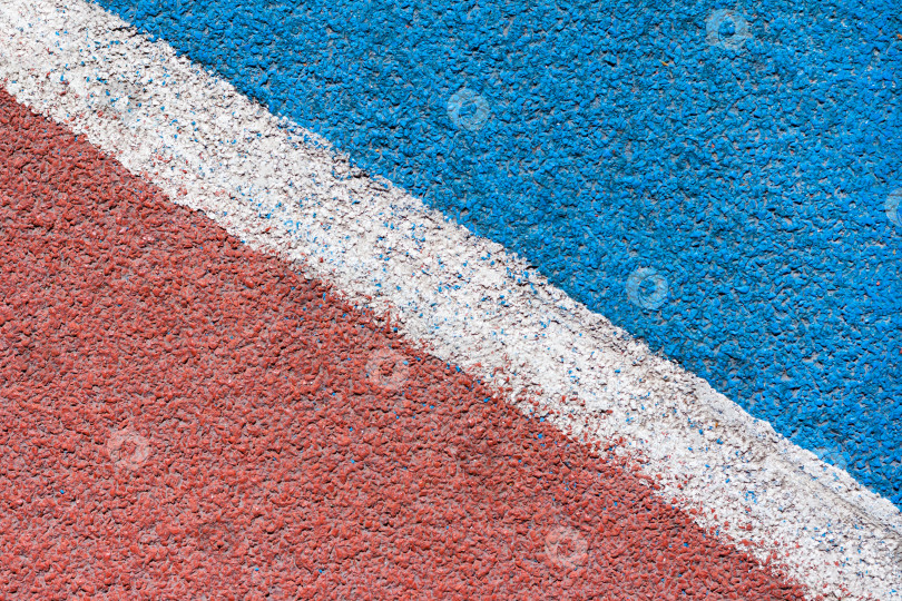 Скачать Абстрактный вид на красно-синем покрытии из синтетической шотландки легкоатлетического стадиона с белой диагональной линией в качестве текстуры, фона фотосток Ozero