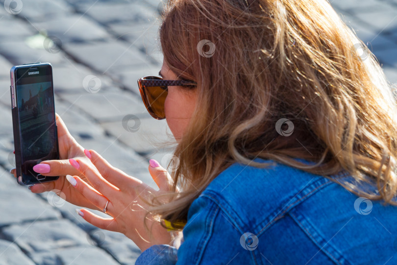 Скачать Москва, Россия, август 2018: Вид сзади на женщину, фотографирующую на телефон на Красной площади (редакционная статья) фотосток Ozero