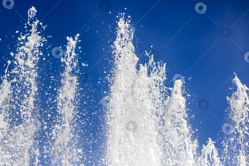 Скачать Брызги жидкости из фонтана на фоне ярко-голубого неба в природном ландшафте фотосток Ozero