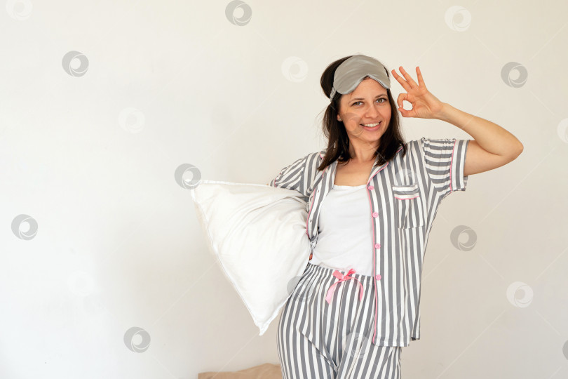 Скачать Женщина, держащая подушку в постели, делает знак рукой "ОК". фотосток Ozero