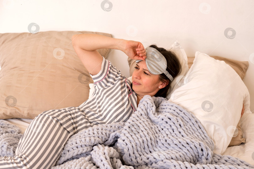 Скачать Женщина чувствует дискомфорт в постели из-за маски для глаз. фотосток Ozero