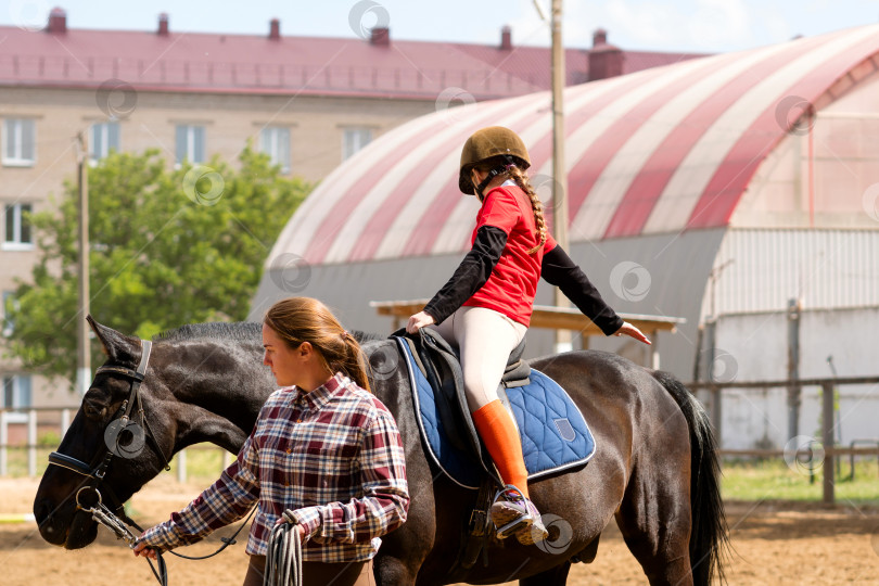 Скачать Инструктор помогает юному наезднику во время занятий конным спортом на открытом воздухе. фотосток Ozero