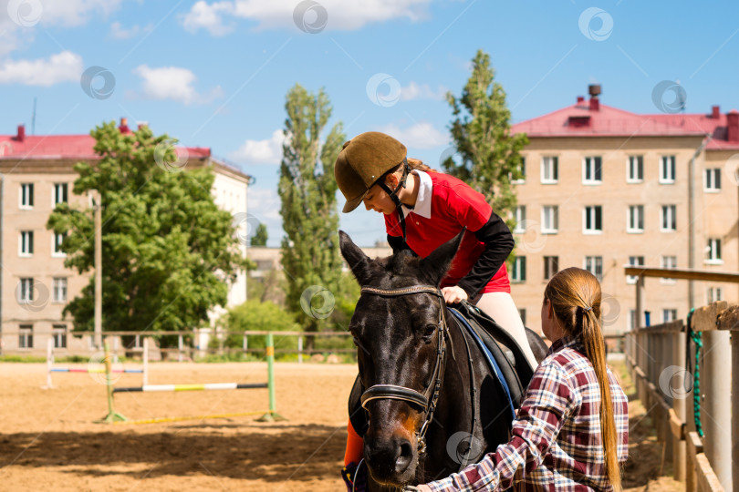 Скачать Юный наездник приноравливается к лошади с помощью инструктора фотосток Ozero