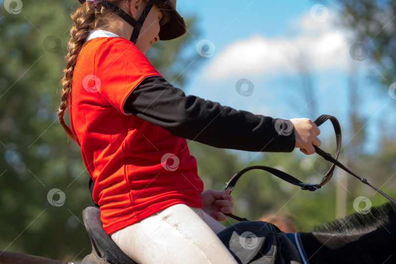 Скачать Юный наездник держит поводья во время тренировки верхом. фотосток Ozero