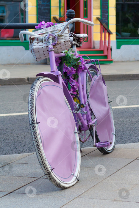 Скачать Инсталляция из винтажного розового велосипеда с цветами в корзине на фоне городской улицы фотосток Ozero