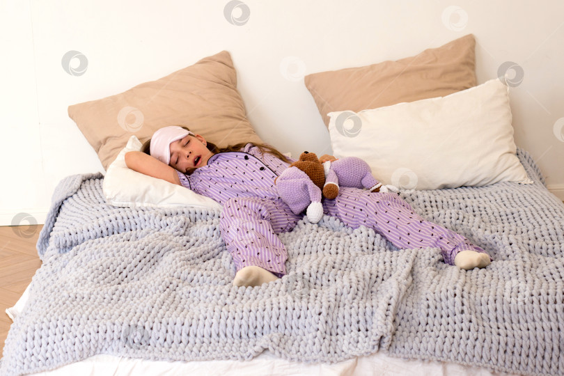 Скачать Девочка дремлет в постели с плюшевым мишкой в фиолетовой пижаме. фотосток Ozero