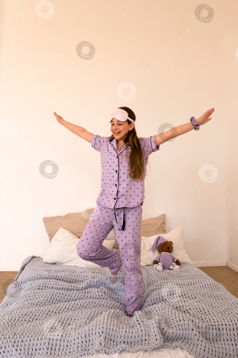 Скачать Счастливая девушка прыгает на кровати, раскинув руки фотосток Ozero
