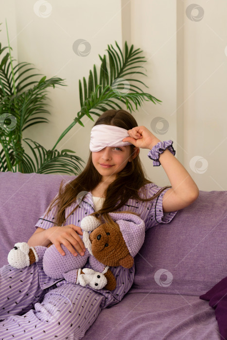 Скачать Девочка поправляет маску для сна, сидя с плюшевым мишкой фотосток Ozero