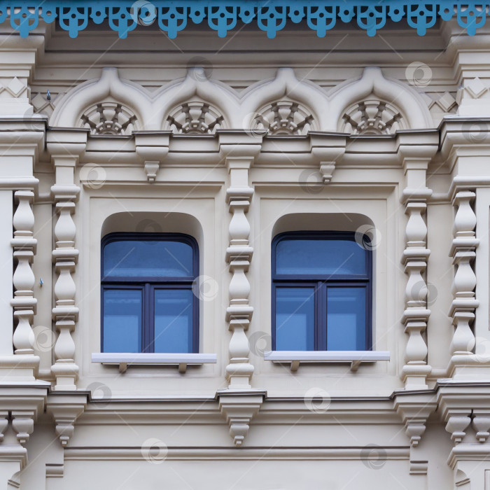 Скачать Вид крупным планом на фасад белого старинного здания с декоративными орнаментами и двумя окнами фотосток Ozero