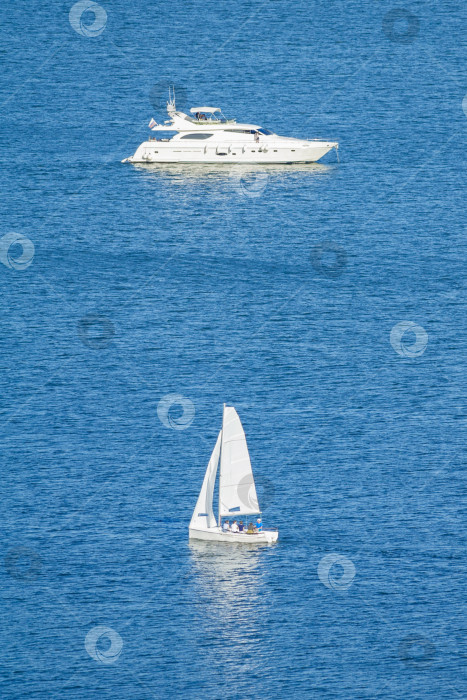 Скачать Вид на небольшое парусное судно и моторную яхту на голубой воде (вертикальная ориентация изображения) фотосток Ozero