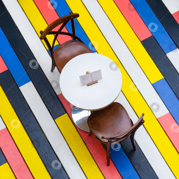 Скачать Вид сверху на круглый стол и стулья на разноцветном деревянном полу в кафе (квадратное соотношение сторон) фотосток Ozero