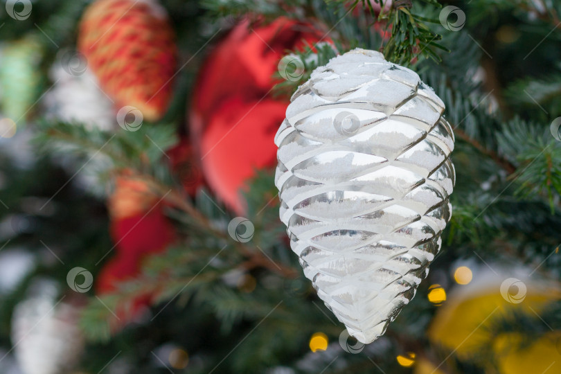 Скачать Крупный план игрушки из сосновой шишки, покрытой инеем, на рождественской елке (небольшая глубина резкости) фотосток Ozero