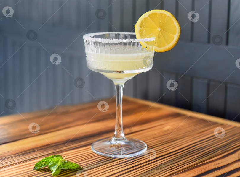 Скачать Алкогольный коктейль "Маргарита" с кусочком лайма на деревянном столе на фоне темной стены с пространством для копирования фотосток Ozero