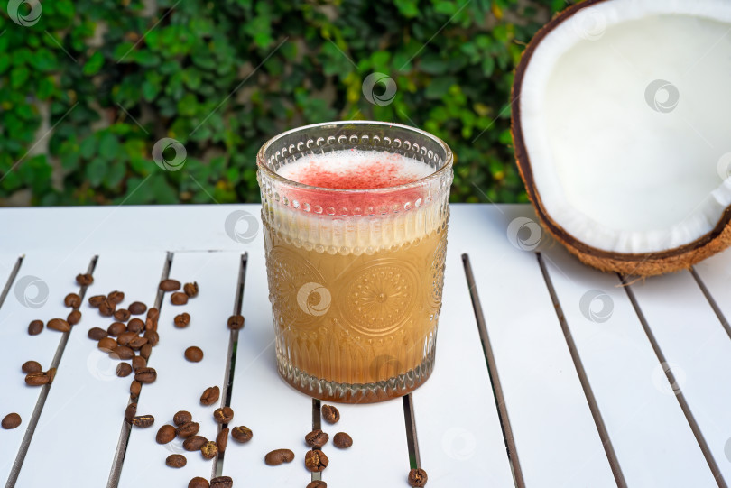 Скачать Raf coffee coconut со свежим кокосом и кофейными зернами на белом деревянном столе на фоне зеленых листьев с пространством для копирования фотосток Ozero