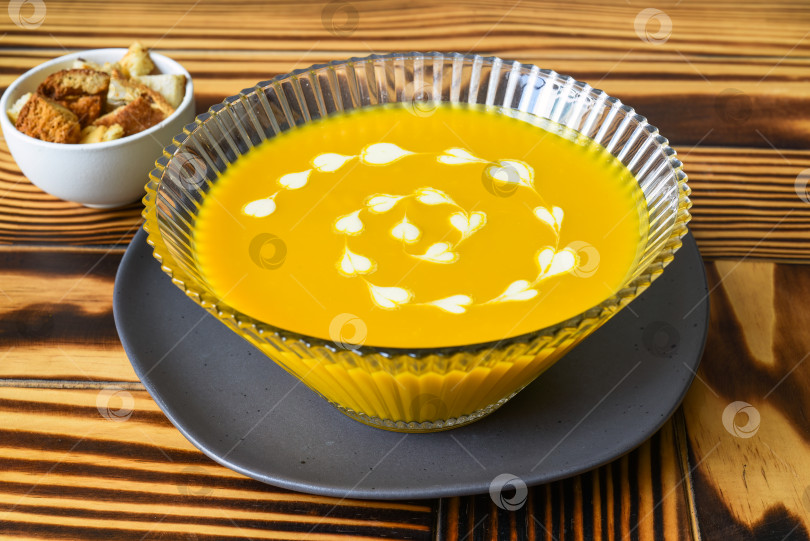 Скачать Тыквенный суп на деревянном столе с крекерами, вид сбоку фотосток Ozero