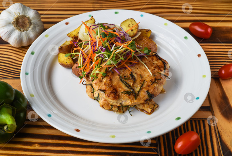 Скачать Куриное филе подается с картофелем, овощами и соусом на белой тарелке крупным планом, вид сбоку фотосток Ozero