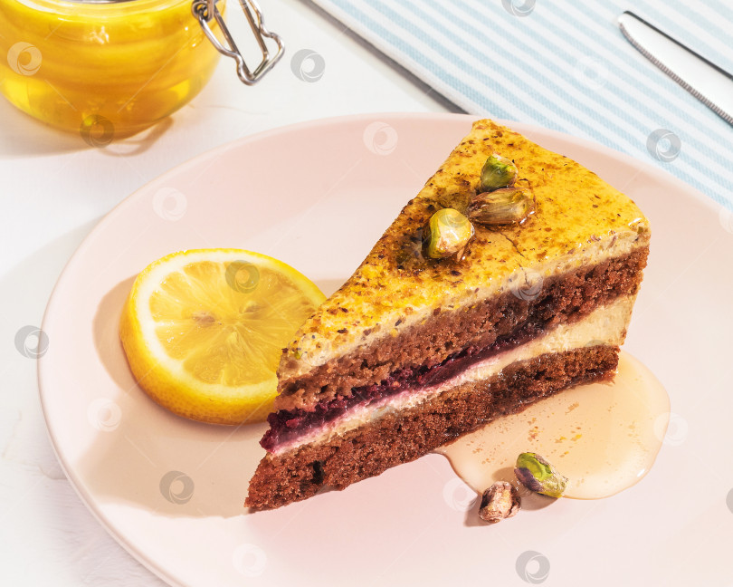 Скачать низкоуглеводный фисташково-лимонный пирог с медом и орехами на розовой тарелке с баночкой меда фотосток Ozero
