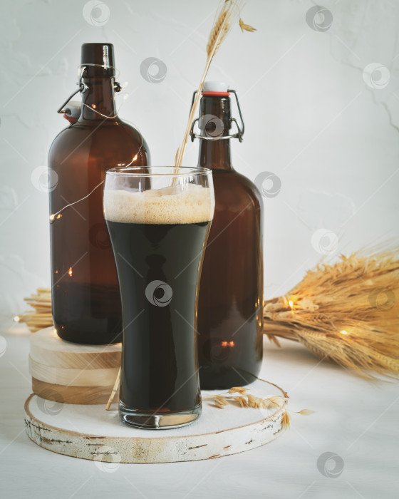 Скачать Бокал темного нефильтрованного пива, две темно-коричневые бутылки и пшеничный букет на белом фоне фотосток Ozero
