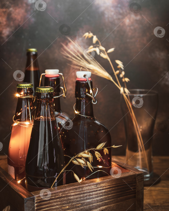 Скачать Бутылки с холодным, светлым и темным нефильтрованным пивом с колосьями пшеницы в пустом бокале на коричневом фоне фотосток Ozero
