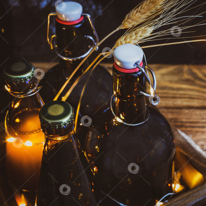 Скачать Стеклянные бутылки с холодным домашним светлым и темным нефильтрованным пивом и мерцающими огоньками на деревянном фоне фотосток Ozero