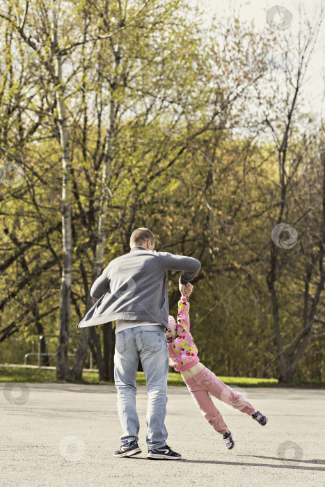 Скачать Папа играет со своей дочерью на заднем дворе. Разматывает его вокруг себя. Семья, папа играет со своей дочерью по выходным фотосток Ozero