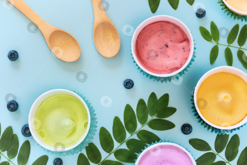 Скачать Разнообразное домашнее, веганское, фруктовое мороженое с листьями, черникой и деревянными ложками на синем фоне фотосток Ozero