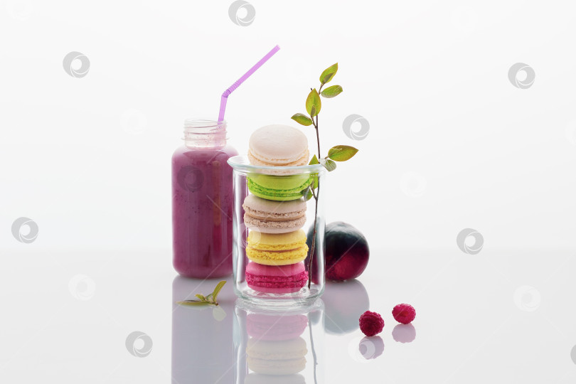 Скачать Миндальное печенье в стеклянной банке с цветущей веточкой и бутылкой овсяно-ягодного коктейля на белом фоне фотосток Ozero