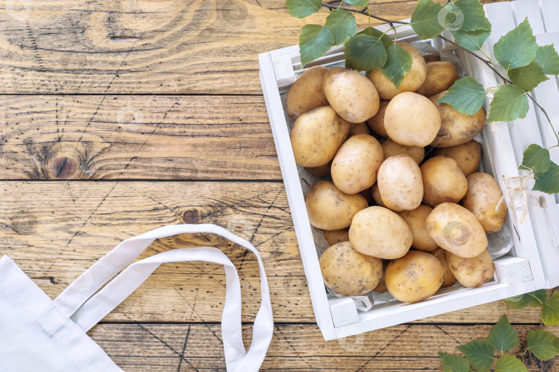 Скачать Деревянная коробка, полная молодого органического фермерского картофеля с местного рынка, на деревянном столе фотосток Ozero