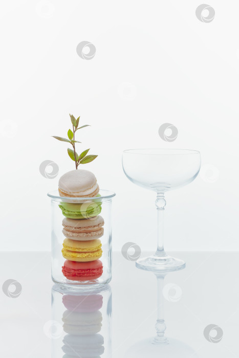 Скачать Вертикальный романтический кулинарный натюрморт с французским десертом - миндальным печеньем с цветущей веточкой и бокалом для коктейля фотосток Ozero
