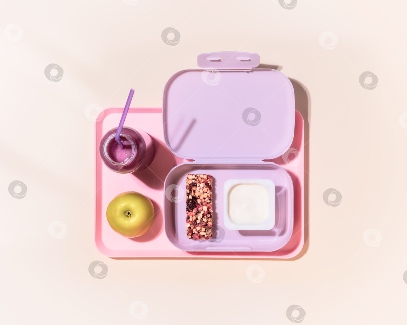 Скачать ланч-бокс с йогуртом, зерновым батончиком, яблочно-овсяным коктейлем и ягодами на розовом фоне фотосток Ozero