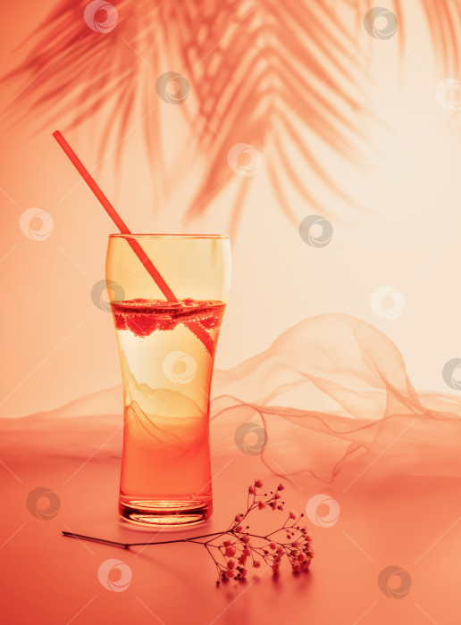 Скачать Бокал натурального газированного лимонада с соломинкой на розовом фоне заката с тенями от пальм фотосток Ozero