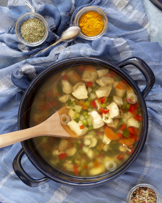 Скачать Большая кастрюля с горячим еврейским куриным супом и специями на синем фоне фотосток Ozero