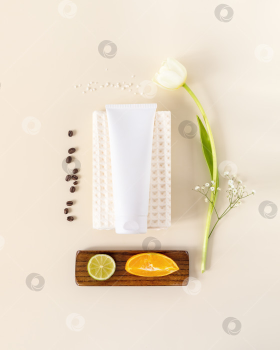 Скачать Натуральная косметическая композиция в тюбике на белом полотенце с тюльпаном, апельсином и лаймом фотосток Ozero