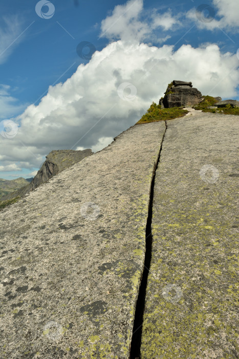 Скачать Прямая длинная трещина, идущая по краю широкой плоской плиты к вершине горы в пасмурный летний день. фотосток Ozero