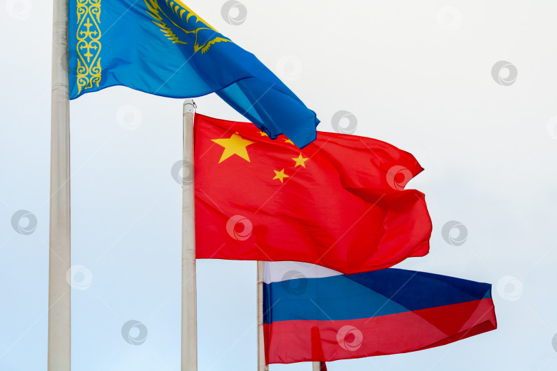 Скачать Вид развевающихся флагов Китая, России и Казахстана на фоне облачного неба фотосток Ozero