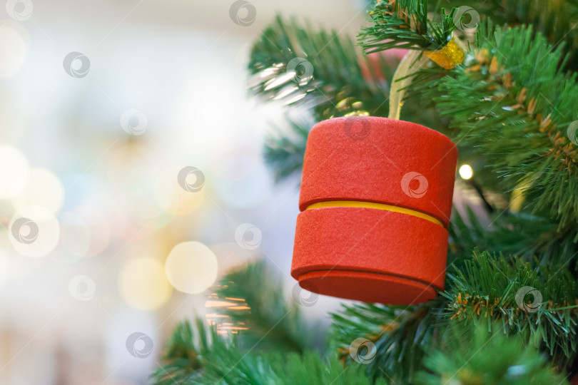 Скачать Крупный план украшения рождественской елки в форме красного цилиндра с размытыми огнями в технике боке на заднем плане (место для копирования) фотосток Ozero