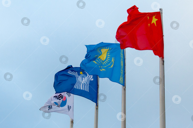 Скачать Вид флагов Китая, Казахстана, Южной Кореи и Содружества Независимых Государств на фоне облачного неба фотосток Ozero