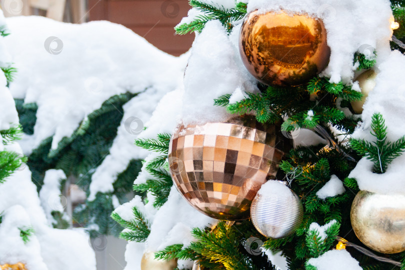 Скачать Заснеженная рождественская елка, украшенная золотыми шарами (крупным планом) фотосток Ozero