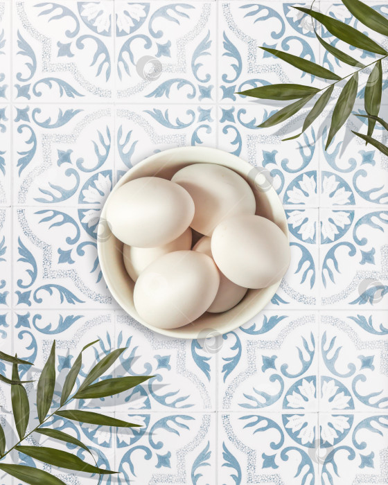 Скачать Белые натуральные яйца в миске на столе, выложенном декоративной плиткой фотосток Ozero