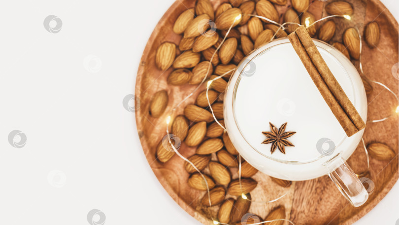 Скачать Чашка миндального молока с палочкой корицы и анисом, орехи на деревянной тарелке фотосток Ozero