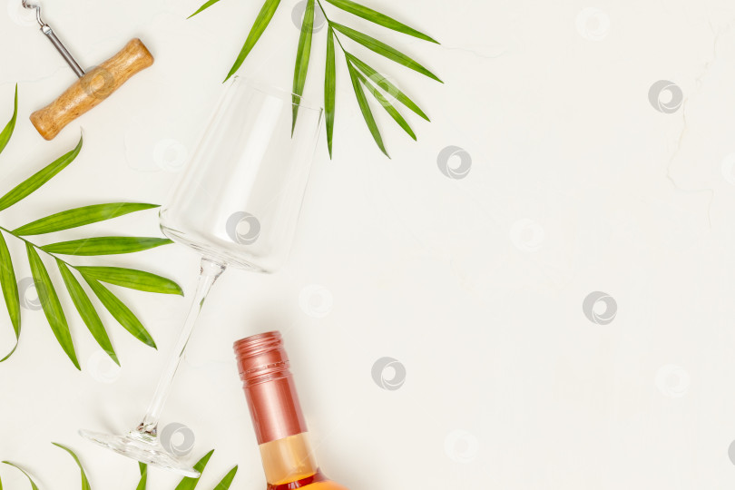 Скачать Пустой бокал для вина, бутылка розового вина и пальмовые листья на белом фоне фотосток Ozero