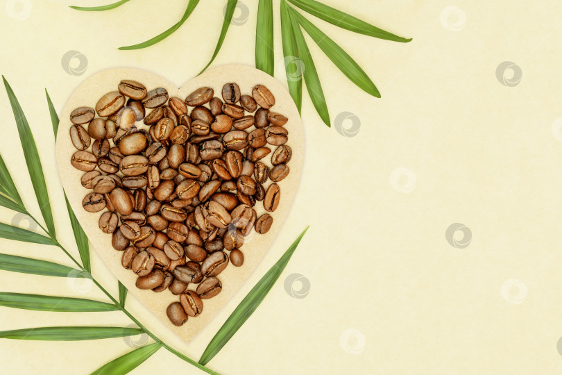 Скачать Кофейные зерна на крафт-бумаге в форме сердца с пальмовыми листьями фотосток Ozero
